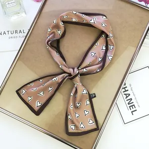 Detail showing elegant silk-feel skinny scarf with white heart pattern and tied knot