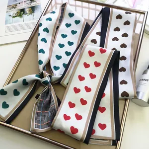 Fashionable narrow Twilly scarves with heart and plaid patterns in a golden tray