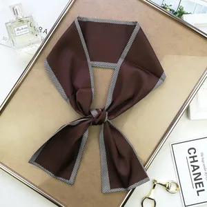 Gros plan d'un foulard en satin marron foncé avec bordures à chevrons noirs et blancs