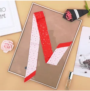 Dettaglio di sciarpa twilly rossa e bianca con stelle e pois su sfondo decorativo