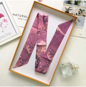 Detail of pink and purple silk twilly scarf with abstract patterns in a gift box
