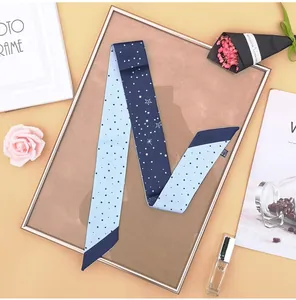 Dettaglio twilly in seta blu con motivi di costellazioni e stelle su fondo elegante