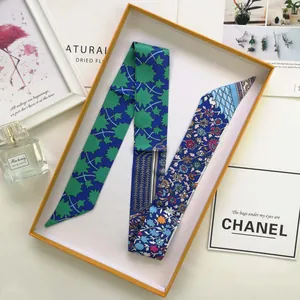 Detail of floral printed twilly silk scarf folded in a gift box with aesthetic accessories