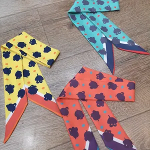 Vista de detalle de tres pañuelos estrechos de seda con motivos florales sobre madera