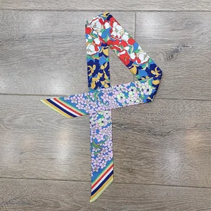 Dettaglio di un foulard in seta a fiori multicolore con punte a righe su legno naturale