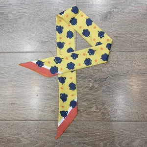 Detalle de un pañuelo estrecho amarillo con patrones geométricos y lunares naranjas