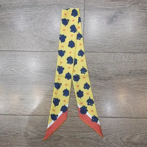 Detalle de pañuelo de seda amarillo con motivos florales azules y bordes rojos vivos