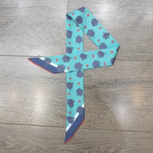 Detalle de pañuelo estrecho verde menta con motivos de nubes y puntos rojos en madera
