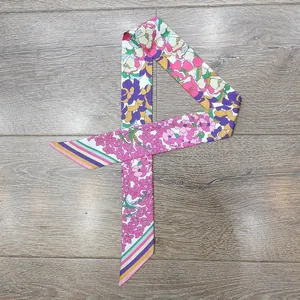 Dettaglio di un foulard sottile in seta con fiori e bordo a righe su base in legno