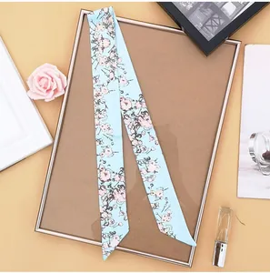 Close-up of light blue floral skinny silk scarf on an elegant display with props