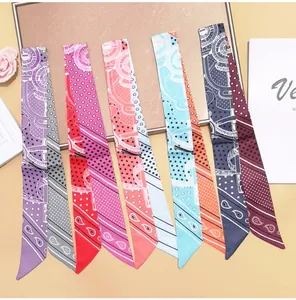Detailed close-up of multiple paisley and floral print skinny silk scarves for bags