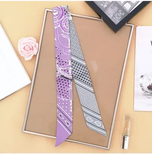 Detail of a purple and grey paisley silk twilly scarf used as a stylish bag handle wrap
