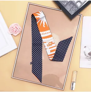 Detail of elegant silk twilly scarf with blue polka dots and orange sunray patterns