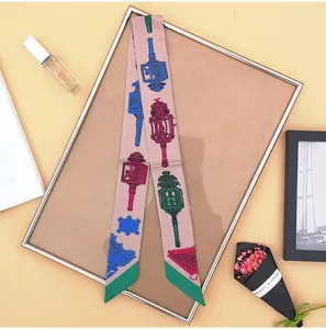 Roze zijden twilly sjaal met vintage lantaarnprints naast parfum en droogbloemen