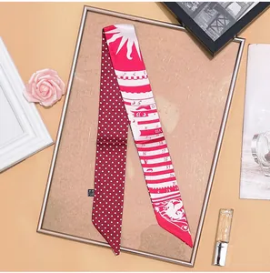 Detailed close-up of a red polka dot long silk scarf with vintage sun patterns in a tray