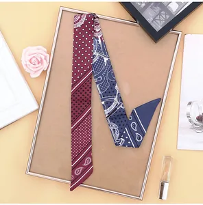 Detail of burgundy and navy paisley twilly scarf wrapped as a luxury bag accessory