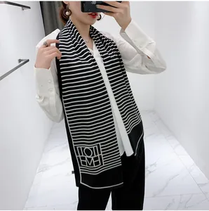 Detailed view of the black and white striped long scarf with geometric logo on end