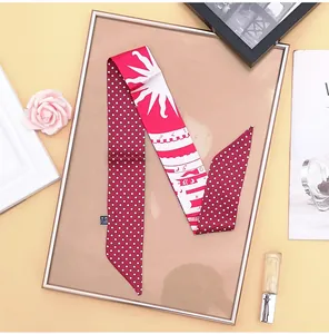 Detail of red and white polka dot silk twilly scarf with decorative patterns and sun motif