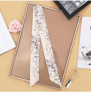 Detailed view of elegant floral pattern on a cream satin skinny scarf on a vanity set