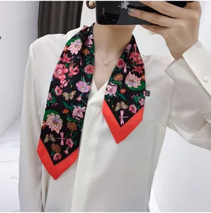 Detail of floral skinny scarf with butterfly patterns and bright orange borders on white shirt