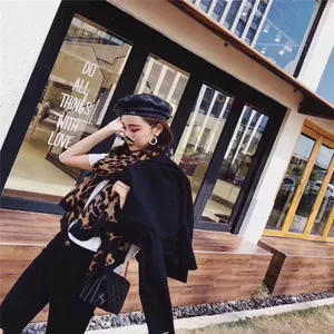 Close-up of leopard print scarf with fringe detail styled on a model in urban street setting