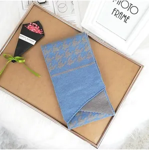 Detail of blue and grey jacquard knit scarf with houndstooth pattern on a wooden tray