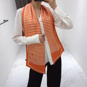 Detail of long orange and white striped silk scarf showing drape and geometric pattern