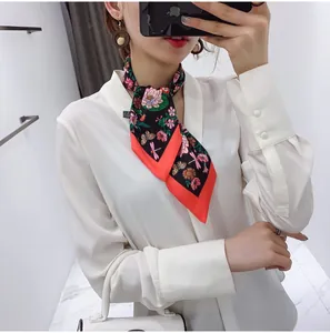 Close-up of elegant floral silk scarf tied in a knot showing lotus and dragonfly prints