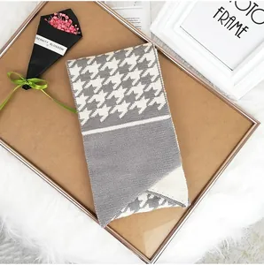 Close-up of houndstooth knit scarf with gray color splicing and detailed stitching texture