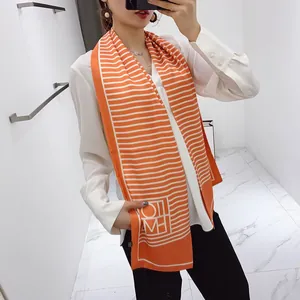Detail of thin orange and white striped satin scarf tied on a white shirt collar