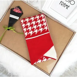 Detail of red and white houndstooth knit scarf styled in a cozy decorative frame