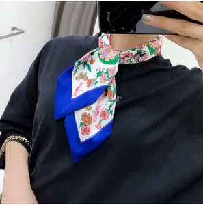 Close-up of floral silk twilly scarf with blue borders tied elegantly around the neck