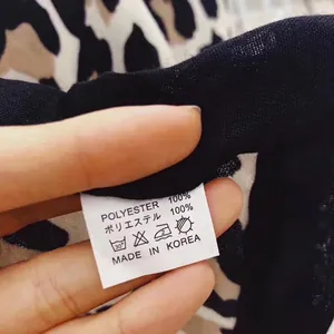 Detailed view of the 100% polyester fabric and origin tag on a leopard print scarf