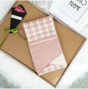 Detail of soft pink houndstooth knit scarf featuring elegant button decorative elements