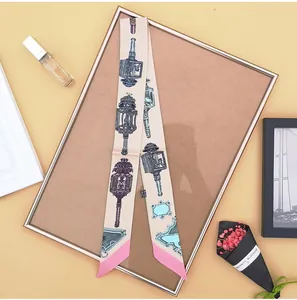 Detail van een smalle zijden sjaal met vintage lantaarnprint op een metalen standaard