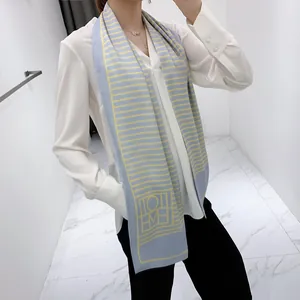 Detail of long silk scarf featuring blue and yellow stripes and geometric patterns