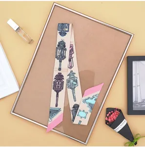 Detail van een smalle zijden sjaal met vintage print op een gouden displayrek