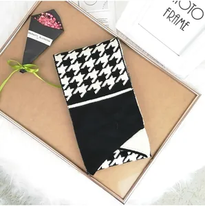 Detail of knitted scarf with black and white houndstooth pattern and button detail