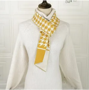 Detail of yellow houndstooth knitted neck gaiter scarf with button on white sweater