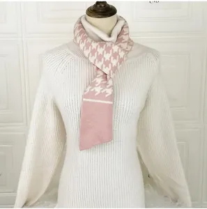 Detail of pink and white houndstooth knit scarf with soft texture on a white turtleneck