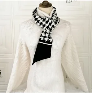 Detail of knit scarf with black and white houndstooth pattern and contrast trim