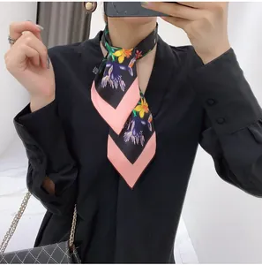 Close-up of a floral silk neck scarf with black and pink geometric patterns worn by a model