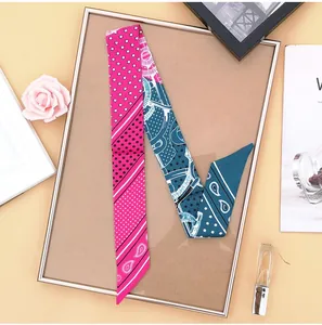 Detail of a pink paisley skinny twilly scarf with star and dot patterns on a gold frame