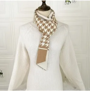 Close-up of knit scarf featuring classic brown and white houndstooth pattern detail