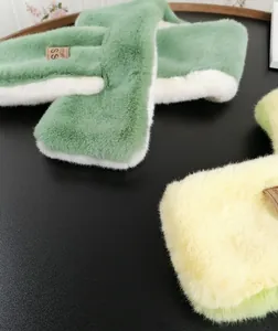 Close-up of soft plush scarves in mint green and yellow with a brown leather label