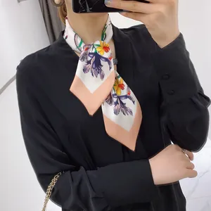 Close-up of floral silk skinny scarf with purple and yellow flowers and pink borders