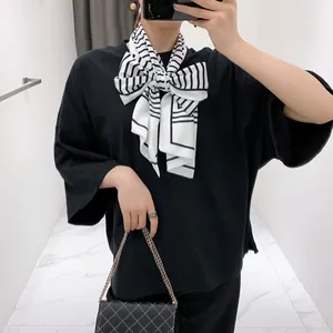 Close-up of lightweight black and white striped scarf tied in a bow on a black t-shirt