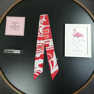 Dettaglio flat lay di un foulard in seta rossa con cuori su un piatto decorativo nero