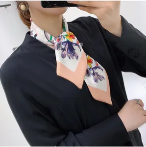 Close-up of a floral silk scarf styled on a dark V-neck top showing elegant drape and pattern