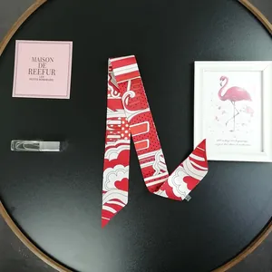 Foulard twilly in seta rossa con cuori e pois esposto su vassoio nero